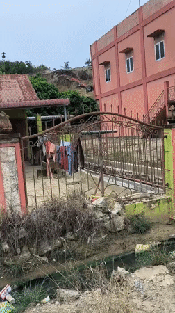Excavator works hillside near homes in Lhokseumawe, Indonesia