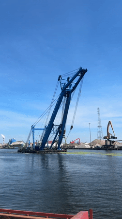 Crane barge and tall ship share Gdańsk harbor on a clear morning
