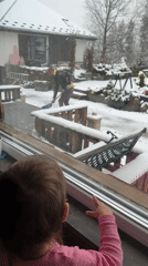 Child watches snow shoveling from window in Wisła