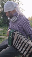 Man plays harmonica outdoors in Yanychi, Russia