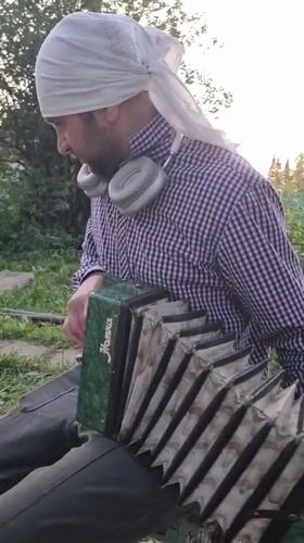 Man plays harmonica outdoors in Yanychi, Russia