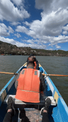 Two People Row Wooden Boat on Lake Under Cloudy Sky