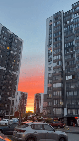 Vivid sunset captured between apartment buildings in Koltushi, Russia