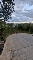 Motorcyclist navigates worn road amid lush vegetation, litter in Ko Samui