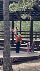 Man blows bubbles for children on forest gazebo