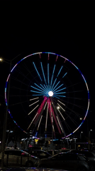 LED-lit Ferris wheel displays colorful light show at night