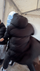 Three people roughhouse in tent structure in Bulgarian village