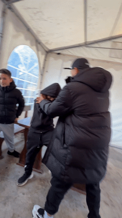 Three people roughhouse in tent structure in Bulgarian village