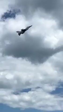 Here's a description of the video:

The video shows a fighter jet performing a sharp turn in the sky. The background consists of a cloudy blue sky. The jet is dark in color and clearly visible against the bright clouds. The sounds of the jet's engine are audible.