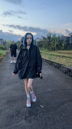 Blue-haired woman walks asphalt path in Kediri, Indonesia