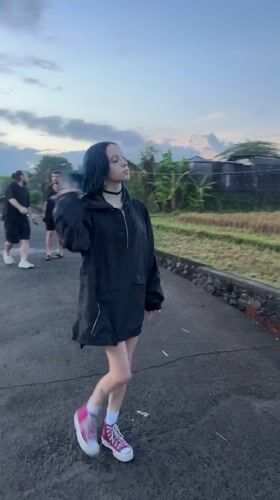 Blue-haired woman walks asphalt path in Kediri, Indonesia