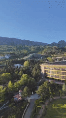 Aerial footage captures landscape with buildings, mountains under clear skies