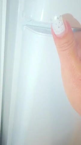 The video shows the interior of a refrigerator. A hand with tattoos reaches into the refrigerator and removes a can of "ALFA" beer. The can is green and white with red lettering. Other items in the refrigerator are not clearly visible.