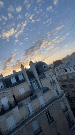 Paris rooftops glow under a warm summer sunset