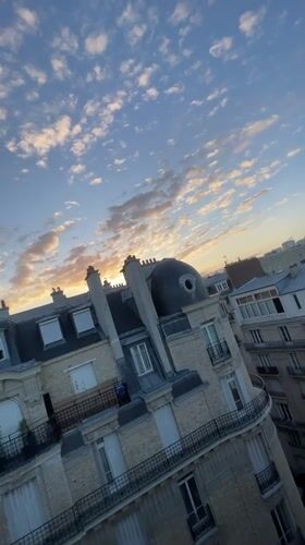 Paris rooftops glow under a warm summer sunset