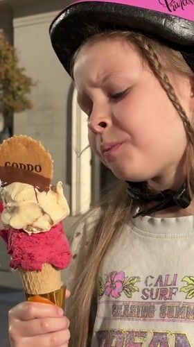 Young girl enjoys large ice cream cone in Tivat