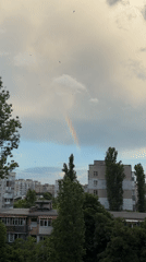 Rainbow appears over city during dramatic evening cloudscape