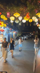 Evening street activity observed in lantern-lit Hội An commercial district