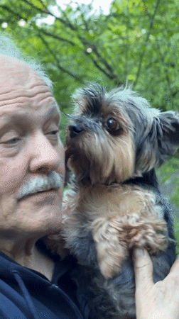 Elderly man enjoys picnic with Yorkshire Terrier in Trudovaya