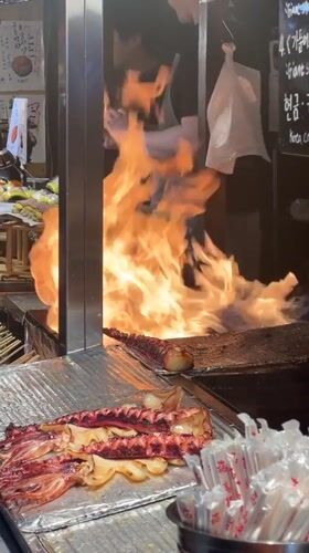 Food stall workers prepare flaming dish in Jeju