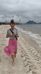 Woman walks barefoot on Vietnamese beach under overcast morning sky