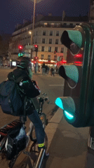Cyclist waits at traffic light in Paris evening