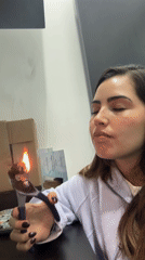 Woman uses pliers to heat material over candle flame