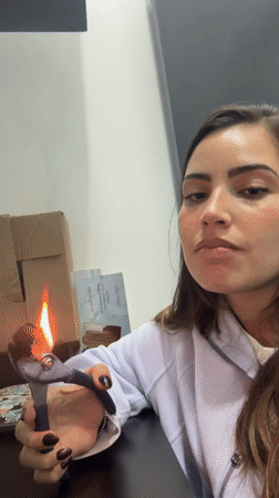 Woman uses pliers to heat material over candle flame