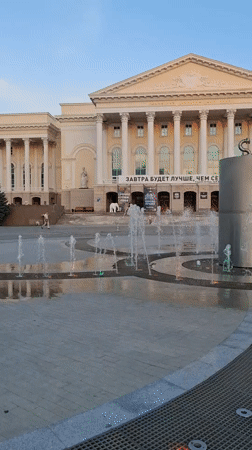 Classical plaza, Cyrillic banner, and city skyline at dusk