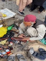 Elderly shoemaker works in busy Quetta market amid local commerce