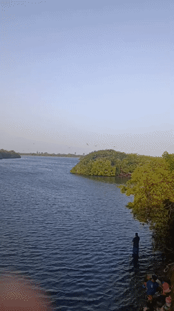Two men wade into choppy waters near Porlamar