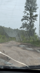 Vehicle travels damaged road with metal barriers in Derhachi