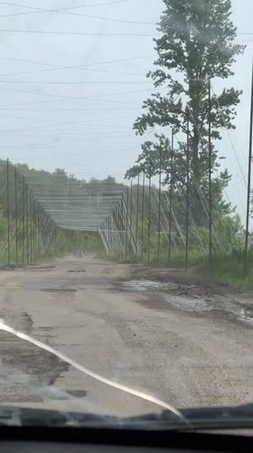 Vehicle travels damaged road with metal barriers in Derhachi