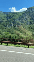 Mountain road driving through green alpine terrain in Nomi, Italy