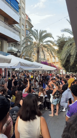 Outdoor crowd celebrates while watching soccer match at cafe