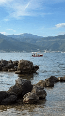 Red boat sails Montenegro coast amid mountain scenery
