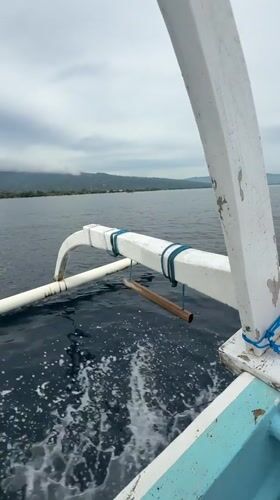 Traditional outrigger canoe filmed sailing calm Indonesian waters