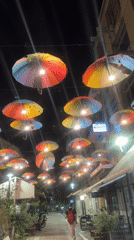 Rainbow umbrella canopy illuminates Karditsa street at night