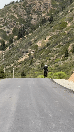 Horseback rider travels mountain road in rural Kyrgyzstan