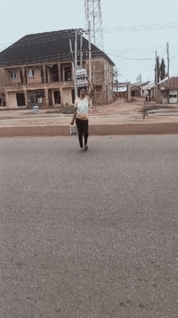 Morning street activity in Bukuru shows pedestrians carrying goods