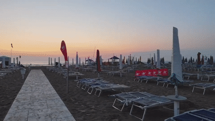 Empty Rimini beach at golden hour, chairs and umbrellas at rest