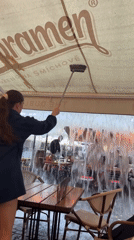 Prague restaurant worker clears water from dining patio awning