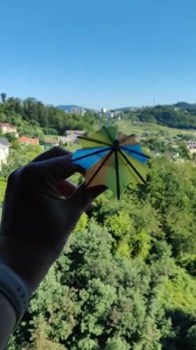 Cocktail umbrella held up against Sochi's sunny green hillside