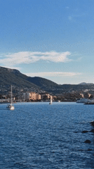 Sailboats navigate waters near Dénia harbor lighthouse, Spain