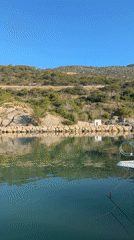 White boat rests on glassy green water off Sitges