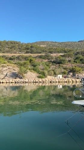 White boat rests on glassy green water off Sitges