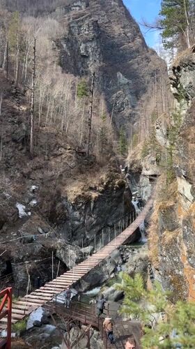 Pedestrians cross suspension bridges over river gorge in Arshan