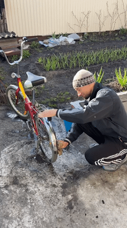 Man cleans bicycle in yard in Ulyanovsk, Russia