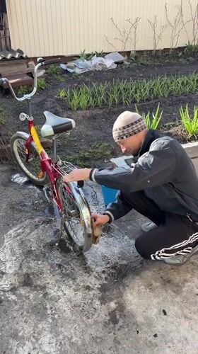 Man cleans bicycle in yard in Ulyanovsk, Russia