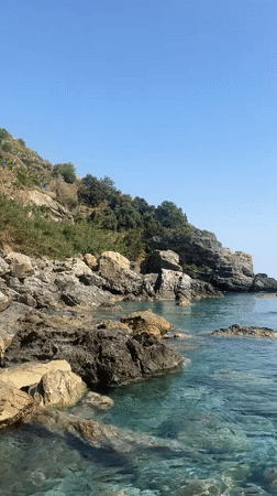 Woman sunbathes on rocky coastline in Gazipaşa, Turkey